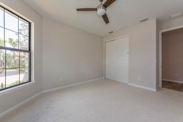 unfurnished bedroom featuring a closet, ceiling fan, and light carpet