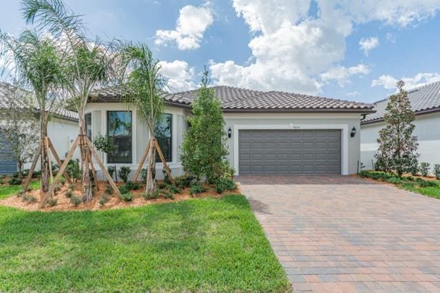 mediterranean / spanish-style house with a garage and a front lawn