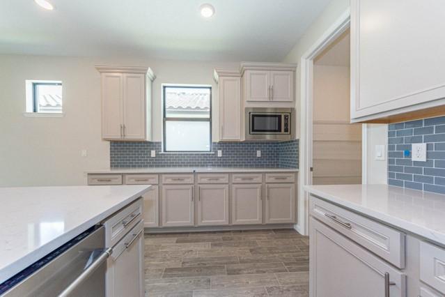 kitchen with light wood-type flooring, decorative backsplash, and appliances with stainless steel finishes