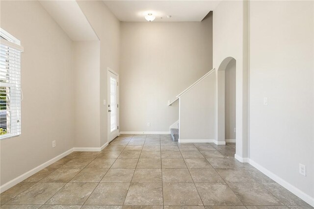 8157 Westfield Cir, Vero Beach, FL 32966 - foyer featuring arched walkways, a high ceiling, baseboards, stairway, and tile patterned floors