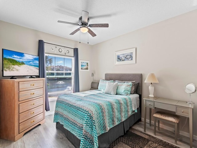 bedroom featuring a ceiling fan, wood finished floors, baseboards, and a textured ceiling