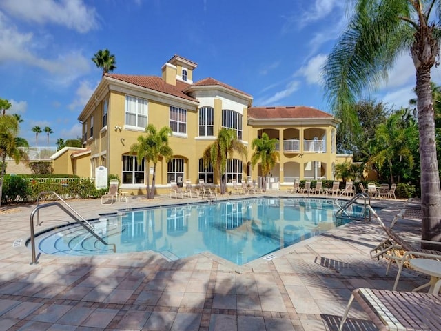 community pool with a patio area and fence