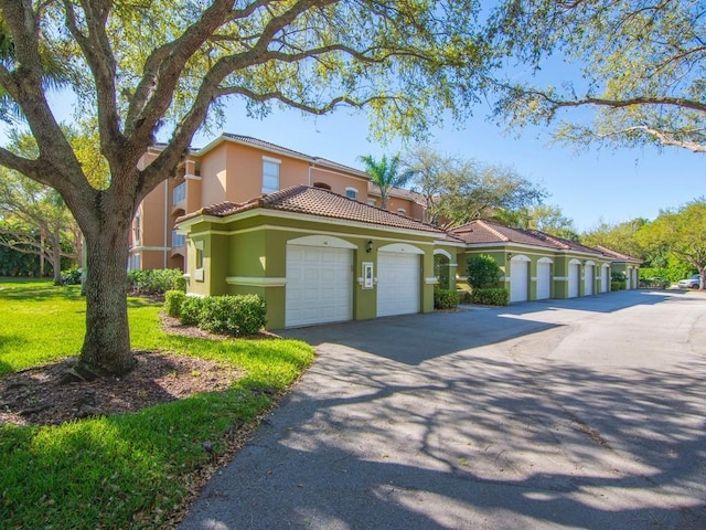 mediterranean / spanish-style house with a tile roof, a garage, a front yard, and stucco siding