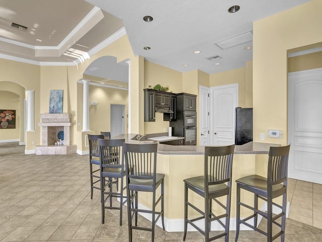 kitchen with a fireplace with raised hearth, visible vents, ornate columns, and arched walkways