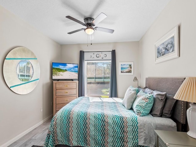 bedroom with baseboards, a textured ceiling, wood finished floors, and a ceiling fan