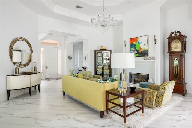 living room with a tray ceiling, an inviting chandelier, and crown molding