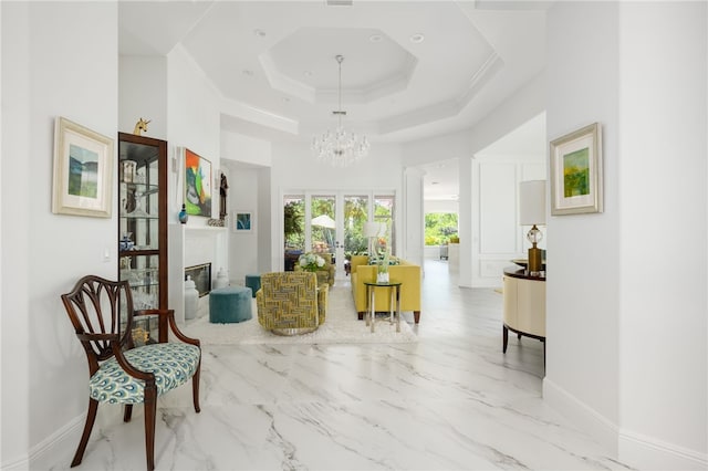 sitting room featuring a raised ceiling, crown molding, french doors, and a notable chandelier