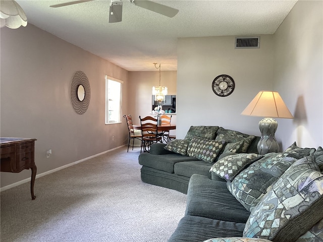 living room featuring carpet, a textured ceiling, and ceiling fan with notable chandelier