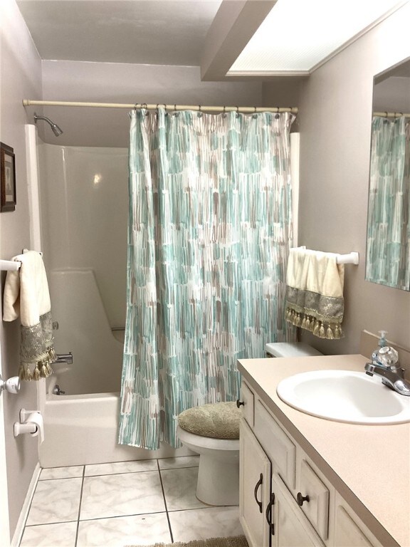 full bathroom with toilet, vanity, tile patterned floors, and shower / bathtub combination with curtain