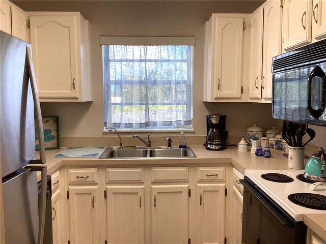 kitchen with white cabinetry, sink, white electric range oven, and stainless steel fridge