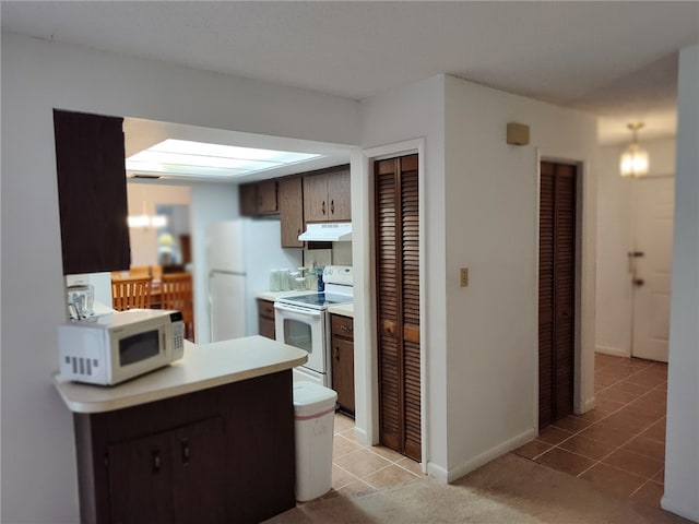 kitchen featuring white appliances, under cabinet range hood, light countertops, and light tile patterned floors