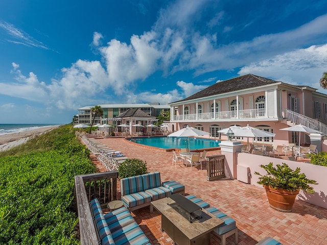 view of pool featuring an outdoor hangout area, exterior bar, a beach view, a patio area, and a water view