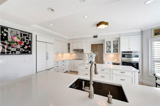 kitchen featuring sink, tasteful backsplash, double oven, white cabinetry, and paneled refrigerator