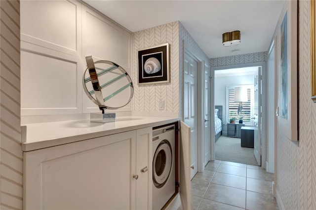 hallway featuring light tile patterned floors, sink, and washer / dryer