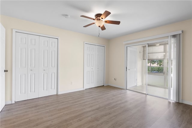 unfurnished bedroom with multiple closets, light hardwood / wood-style flooring, and ceiling fan