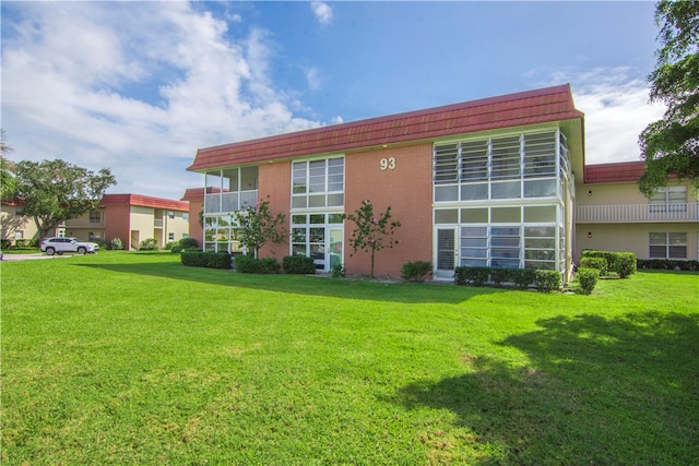 back of property with a lawn and a balcony