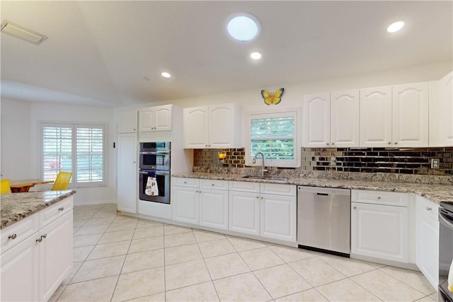 kitchen featuring sink, light tile patterned flooring, stainless steel appliances, white cabinets, and light stone counters