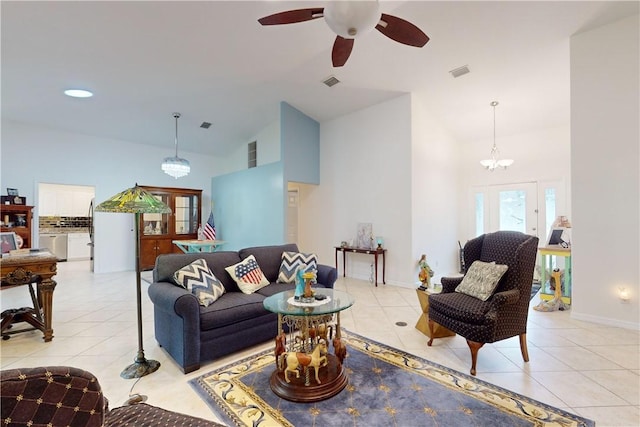 living room featuring vaulted ceiling, light tile patterned flooring, and ceiling fan with notable chandelier