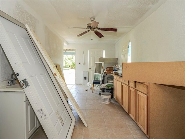 interior space with ceiling fan, light tile patterned floors, and a sink