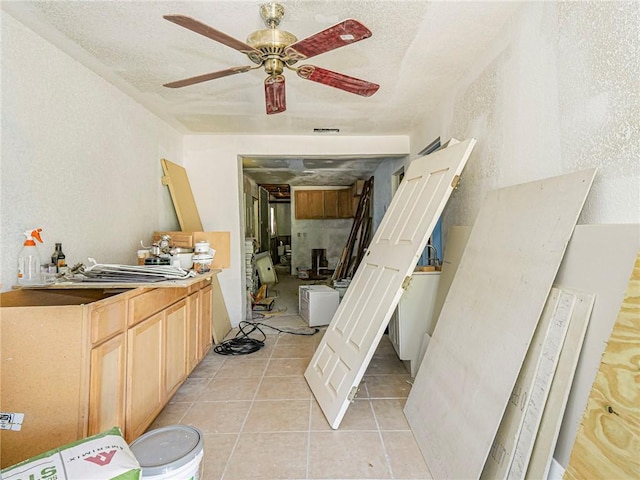 kitchen with light tile patterned floors, visible vents, ceiling fan, a textured ceiling, and a textured wall