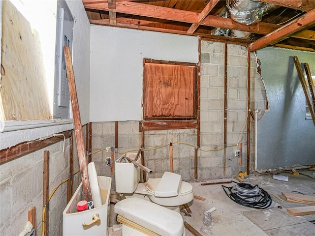 bathroom featuring concrete block wall and toilet