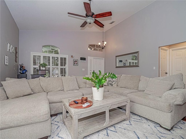 living room with ceiling fan with notable chandelier and vaulted ceiling