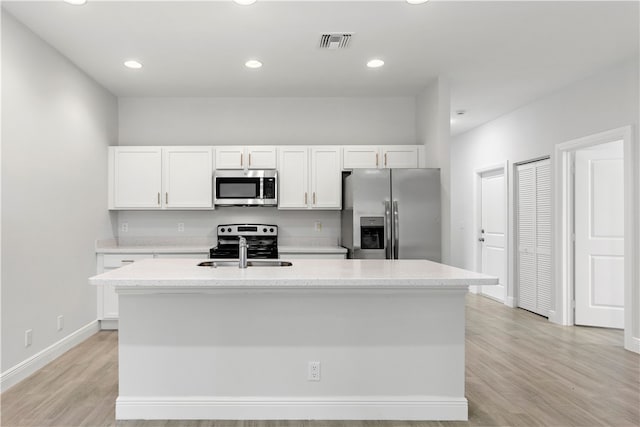 kitchen with sink, white cabinetry, a center island with sink, light hardwood / wood-style flooring, and stainless steel appliances