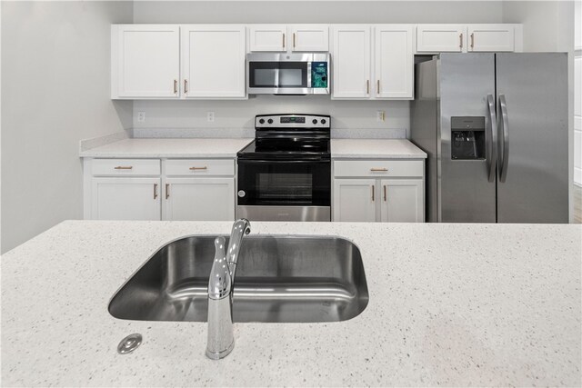 775 11th Ave SW, Vero Beach, FL 32962 - kitchen featuring stainless steel appliances, white cabinetry, a sink, and light stone counters