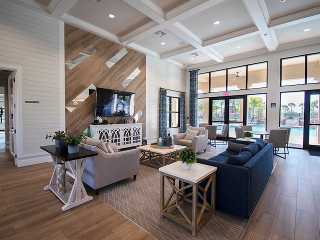 living room featuring hardwood / wood-style flooring, wooden walls, a high ceiling, and french doors