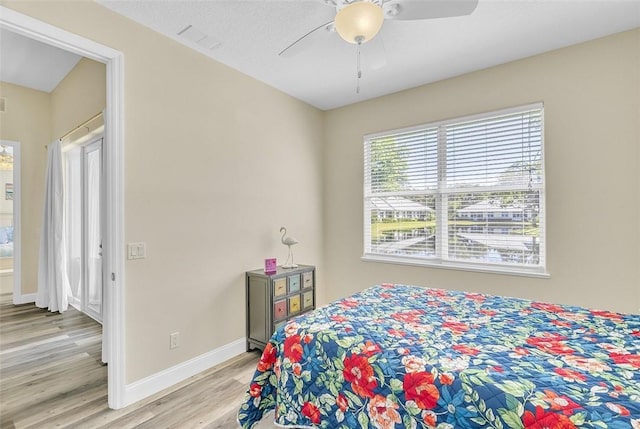 bedroom with light wood-style floors, baseboards, and ceiling fan