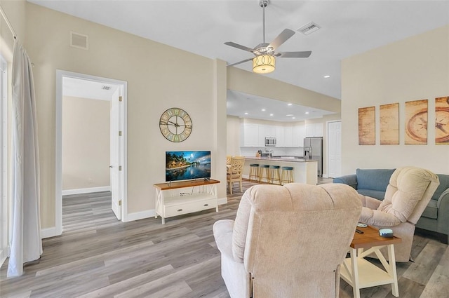 living area with visible vents, baseboards, a ceiling fan, and light wood finished floors