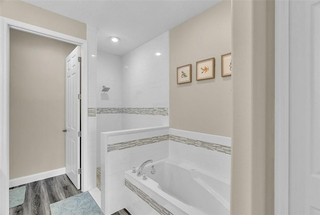 full bathroom featuring wood finished floors, baseboards, tiled shower, and a bath