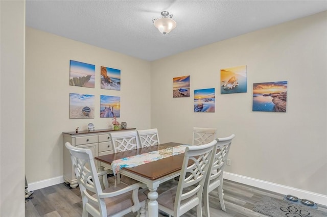 dining room featuring baseboards, a textured ceiling, and wood finished floors