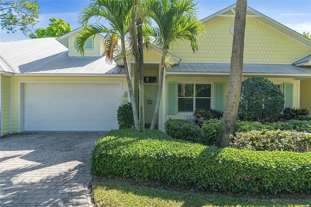 view of front of property with decorative driveway, a garage, and metal roof