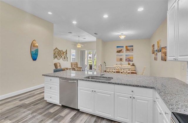 kitchen with a sink, light wood-type flooring, light stone counters, and appliances with stainless steel finishes