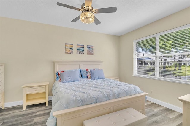 bedroom with a ceiling fan, baseboards, and light wood-type flooring