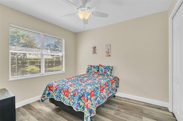 bedroom featuring a closet, baseboards, wood finished floors, and a ceiling fan