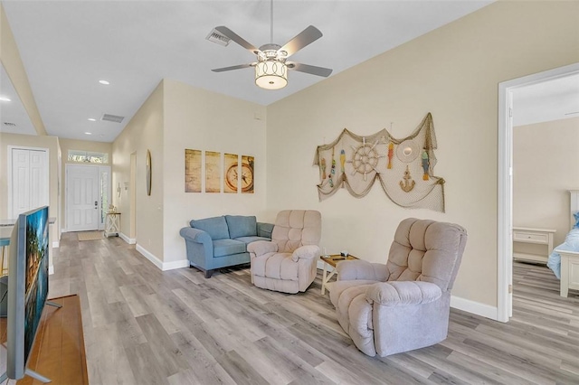 living room with visible vents, baseboards, light wood-style flooring, and a ceiling fan