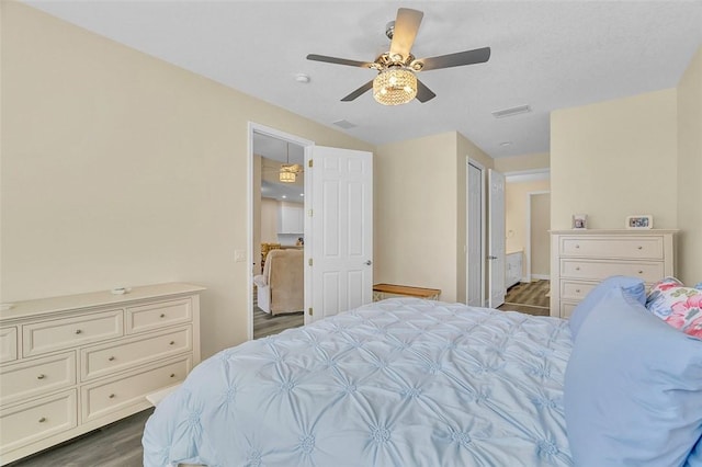 bedroom featuring dark wood-type flooring, visible vents, and ceiling fan