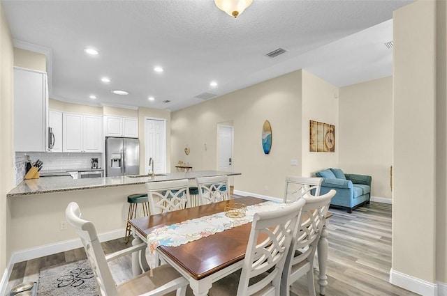 dining space featuring light wood-type flooring, visible vents, baseboards, and recessed lighting