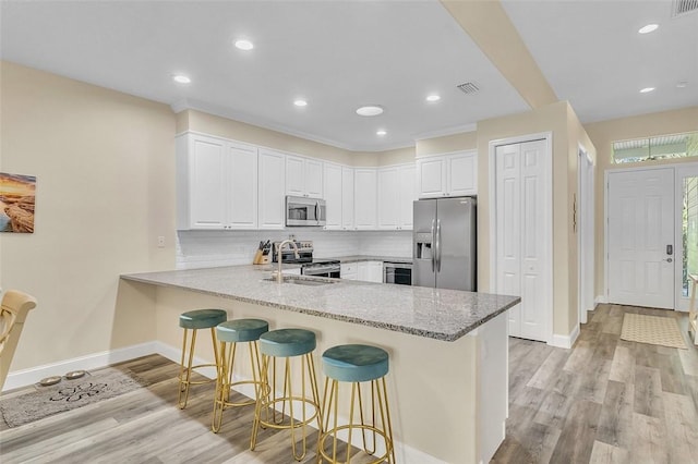 kitchen featuring visible vents, a breakfast bar, decorative backsplash, appliances with stainless steel finishes, and a peninsula