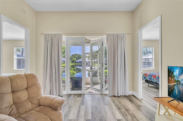 doorway with wood finished floors, visible vents, a wealth of natural light, and baseboards