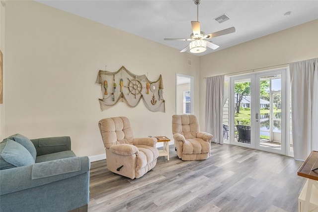 living area featuring visible vents, baseboards, french doors, wood finished floors, and a ceiling fan