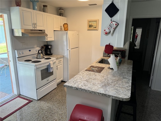 kitchen with white cabinets, white appliances, backsplash, and a breakfast bar area