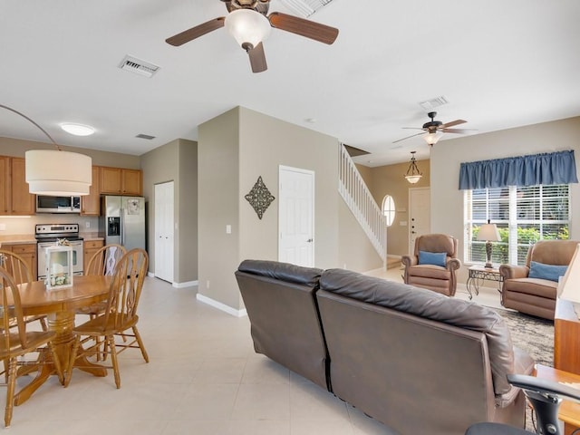 living area with stairway, baseboards, visible vents, and a ceiling fan