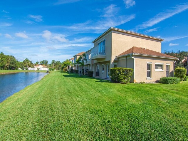 view of front of house with concrete driveway, a balcony, an attached garage, a front lawn, and stucco siding