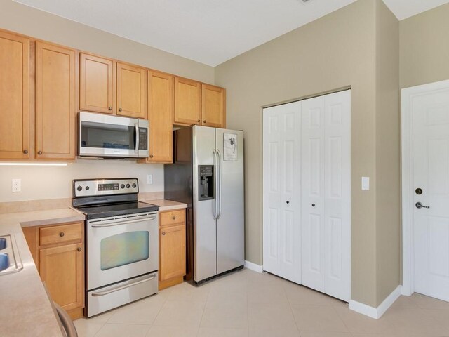 kitchen with light countertops, appliances with stainless steel finishes, light brown cabinets, and baseboards