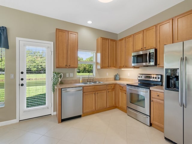 kitchen with light countertops, appliances with stainless steel finishes, light tile patterned flooring, and a sink