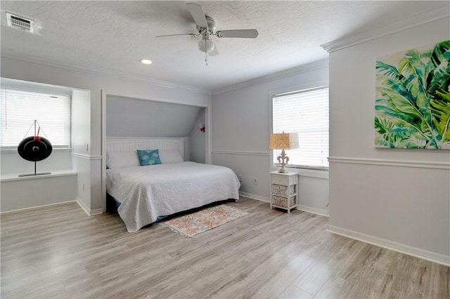 bedroom featuring ceiling fan, ornamental molding, light hardwood / wood-style flooring, and a textured ceiling