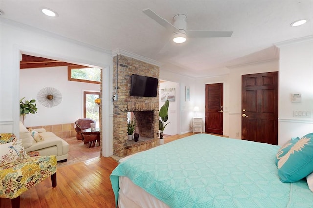 bedroom with ornamental molding, wood-type flooring, and a fireplace